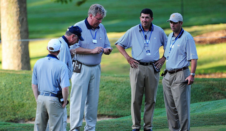 Rules officials congregate at Atlanta Athletic Club's 14th hole during the PGA Championship.
