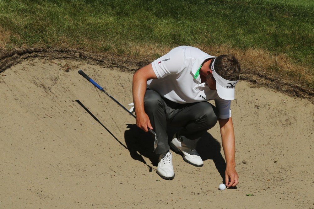 Luke Donald moves a stone from a bunker during the third round of the BMW PGA Championship in 2012. (David Cannon/Getty Images)